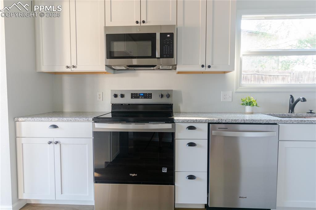 Image 13 of 37: Kitchen with appliances with stainless steel finishes, white cabinetry, and