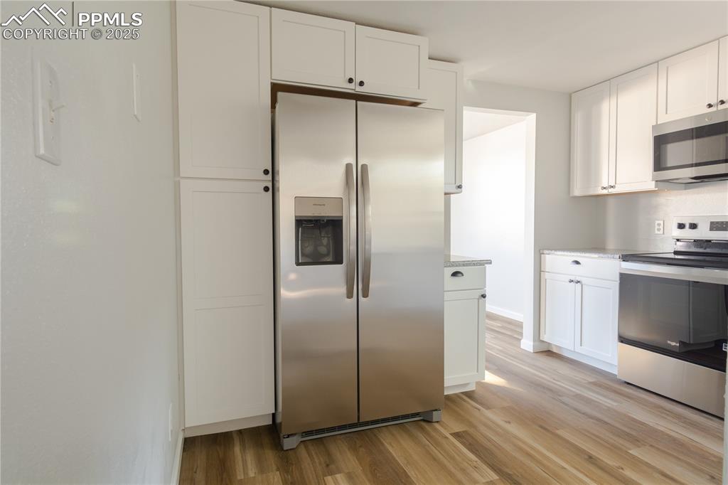 Image 14 of 37: Kitchen featuring appliances with stainless steel finishes, light wood-styl