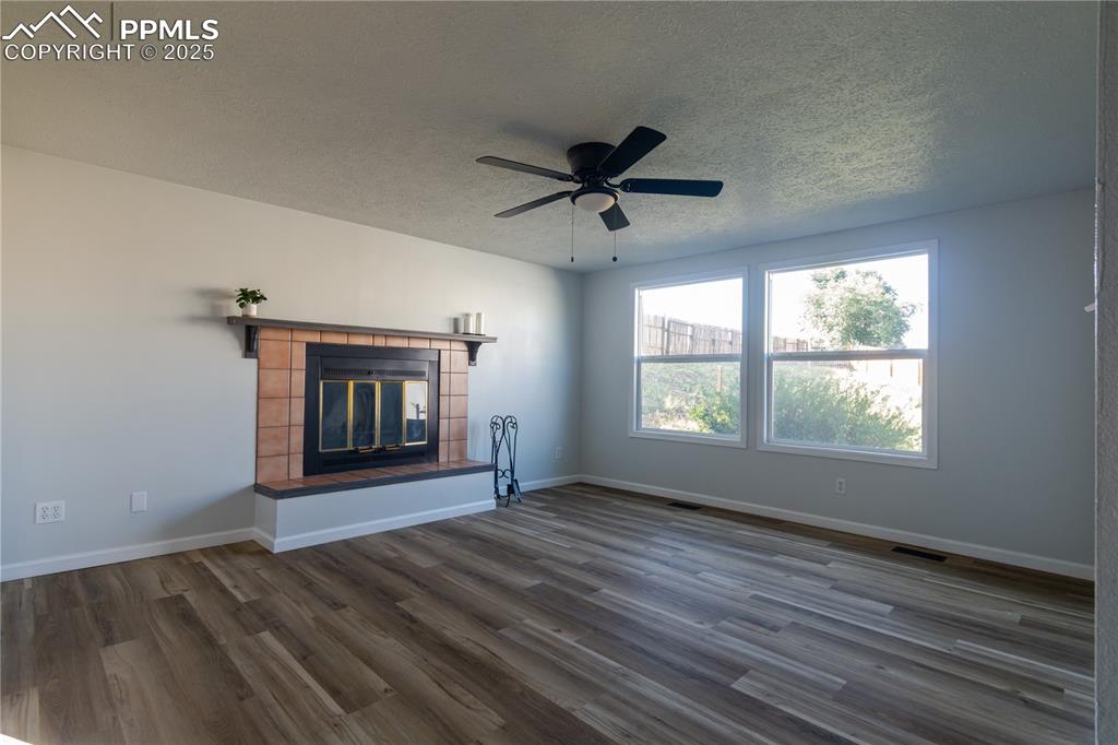 Image 17 of 37: Unfurnished living room featuring  wood-style floors, a tile fireplace, a t