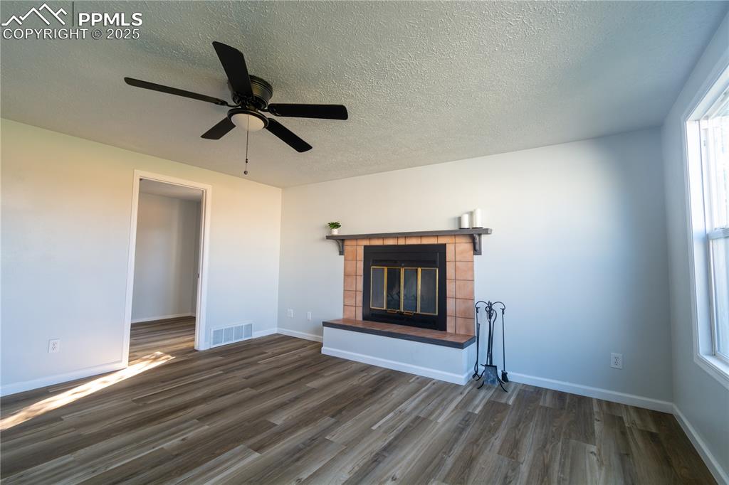 Image 18 of 37: Unfurnished living room featuring a fireplace, a textured ceiling, dark woo
