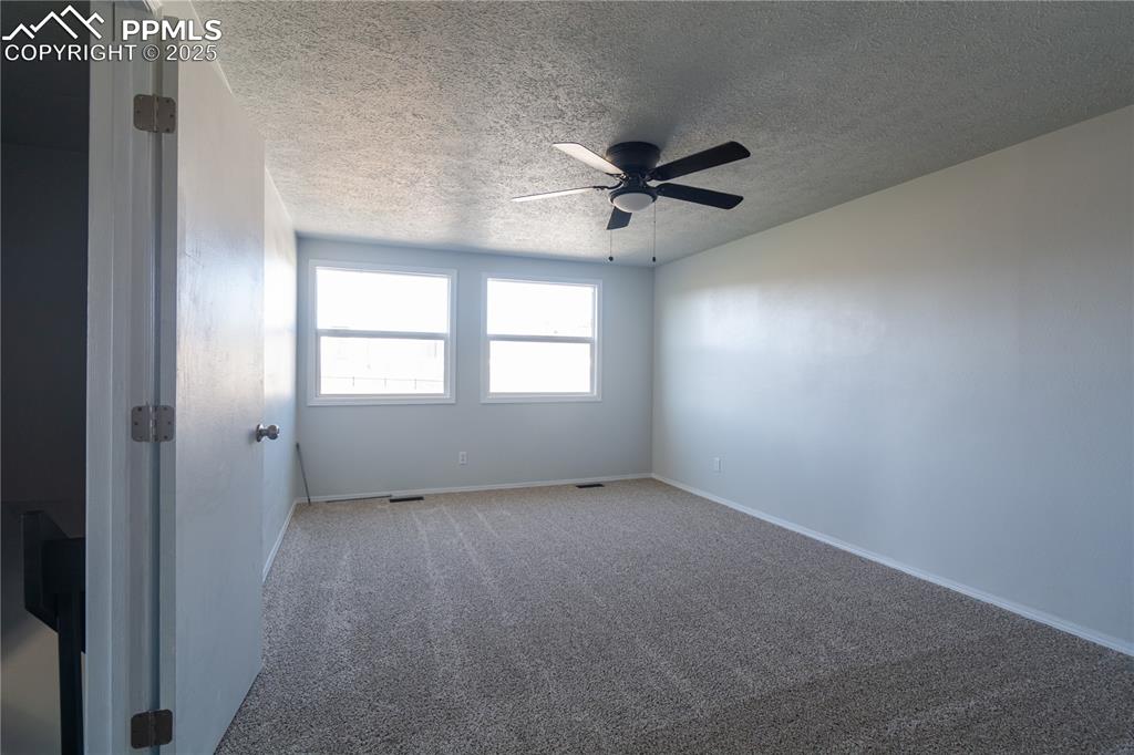 Image 22 of 37: Carpeted empty room with a textured ceiling and a ceiling fan
