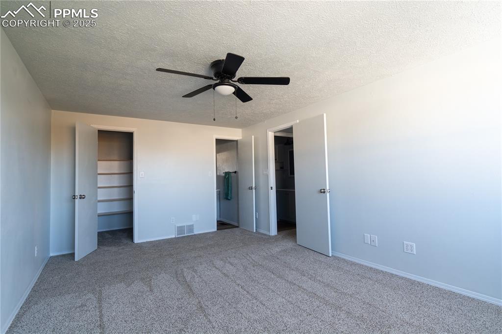Image 23 of 37: Unfurnished bedroom with carpet, a textured ceiling, a ceiling fan, and mul