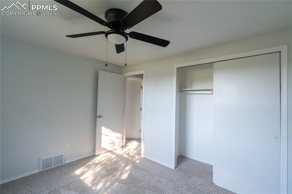 Image 32 of 37: Unfurnished bedroom with carpet, a closet, and a ceiling fan