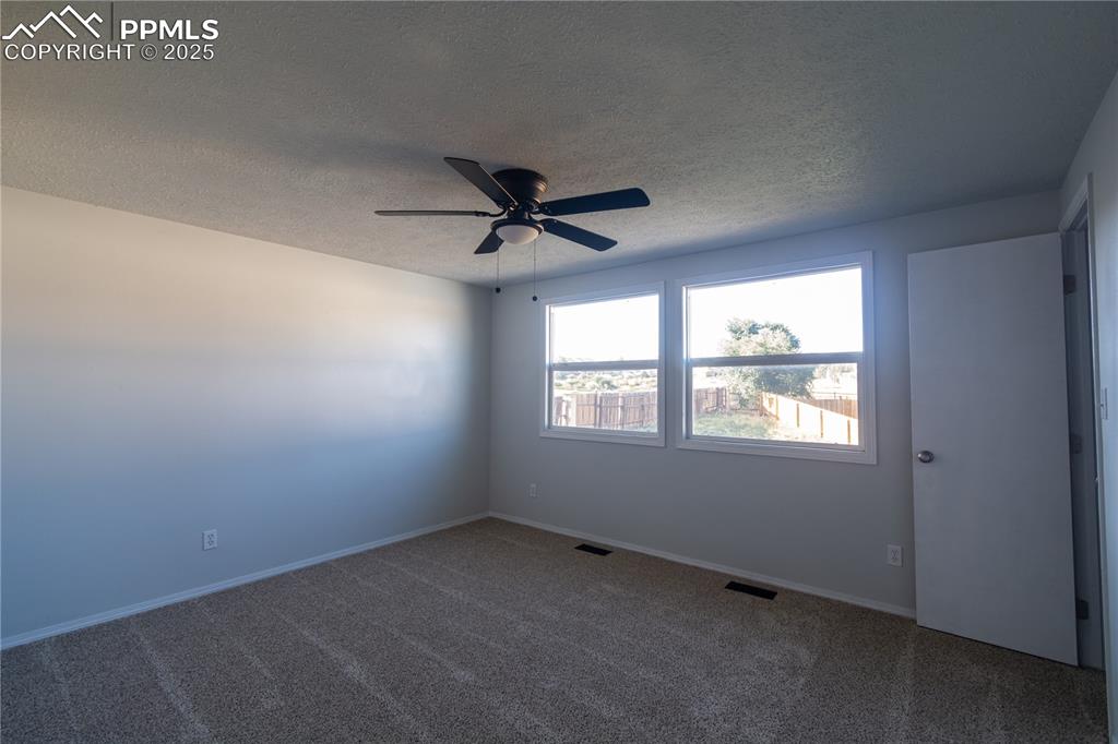 Image 33 of 37: Carpeted empty room with a textured ceiling and a ceiling fan
