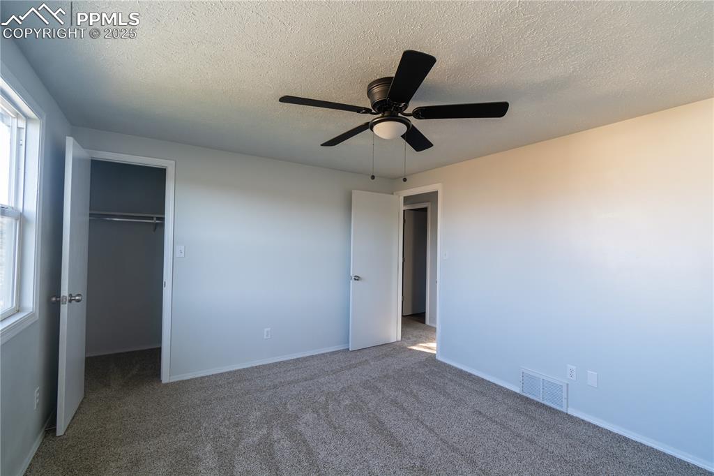 Image 34 of 37: Unfurnished bedroom with a walk in closet, carpet floors, a textured ceilin