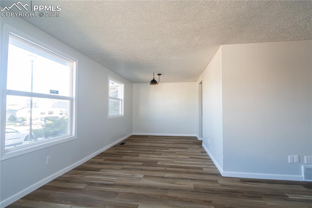 Image 8 of 37: Spare room featuring  wood-type flooring and a textured ceiling