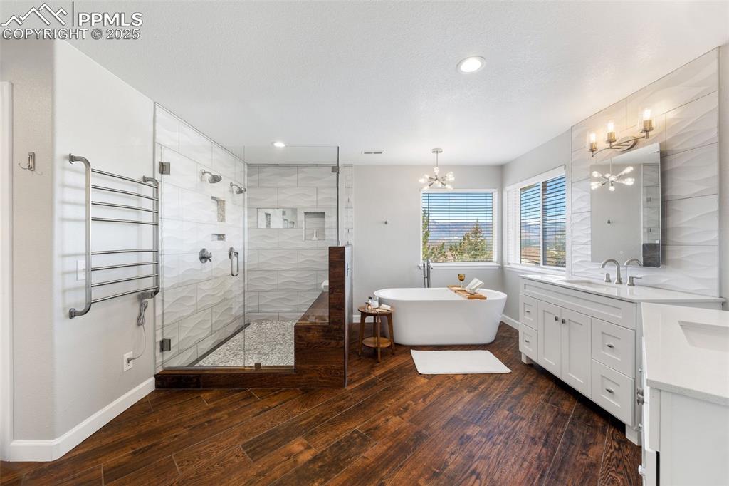 Image 29 of 50: Bathroom featuring vanity, a soaking tub, a shower stall, wood-type floorin