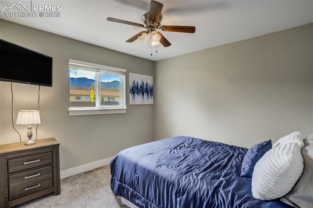 Image 20 of 29: Bedroom with light colored carpet and ceiling fan