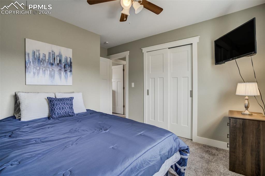 Image 21 of 29: Bedroom with light colored carpet, ceiling fan, and a closet