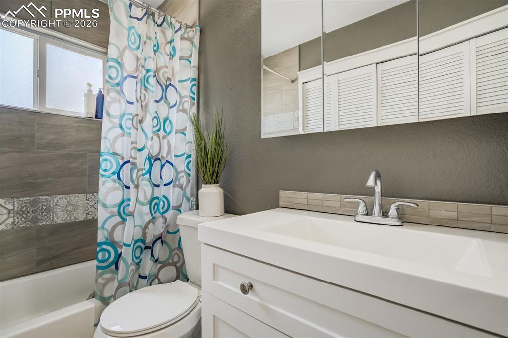 Image 22 of 29: Full bathroom featuring a textured wall, shower / bath combo, and vanity