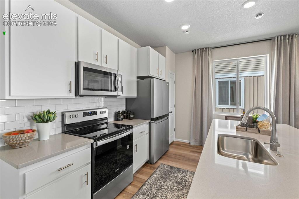 Image 11 of 25: Modern kitchen featuring white cabinetry, stainless steel appliances includ