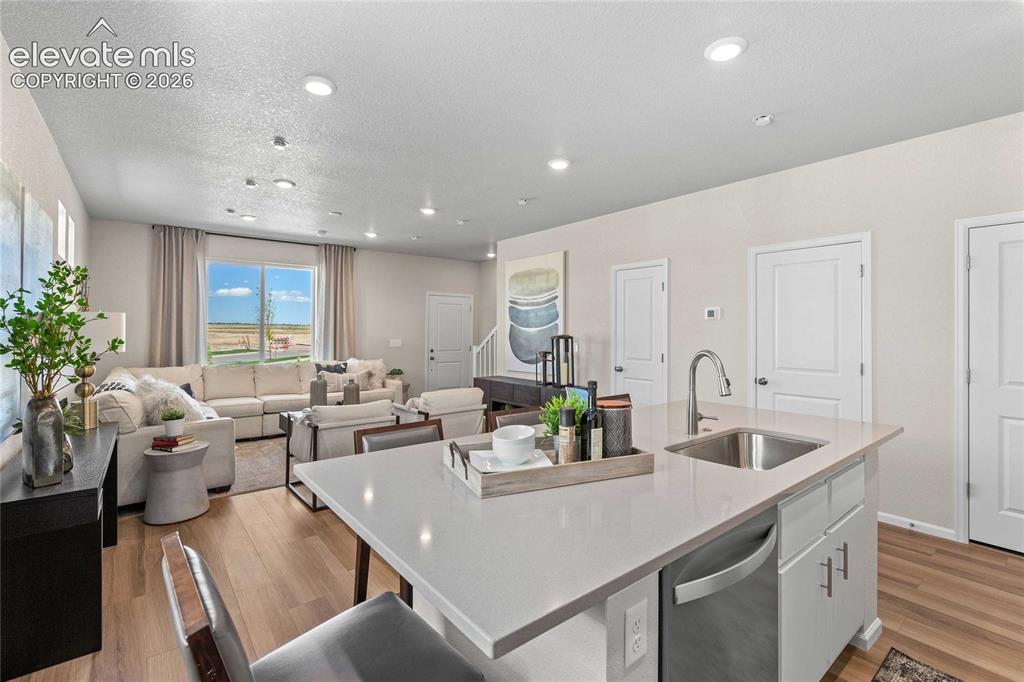 Image 12 of 25: Open-concept kitchen and living area featuring white shaker cabinetry with 