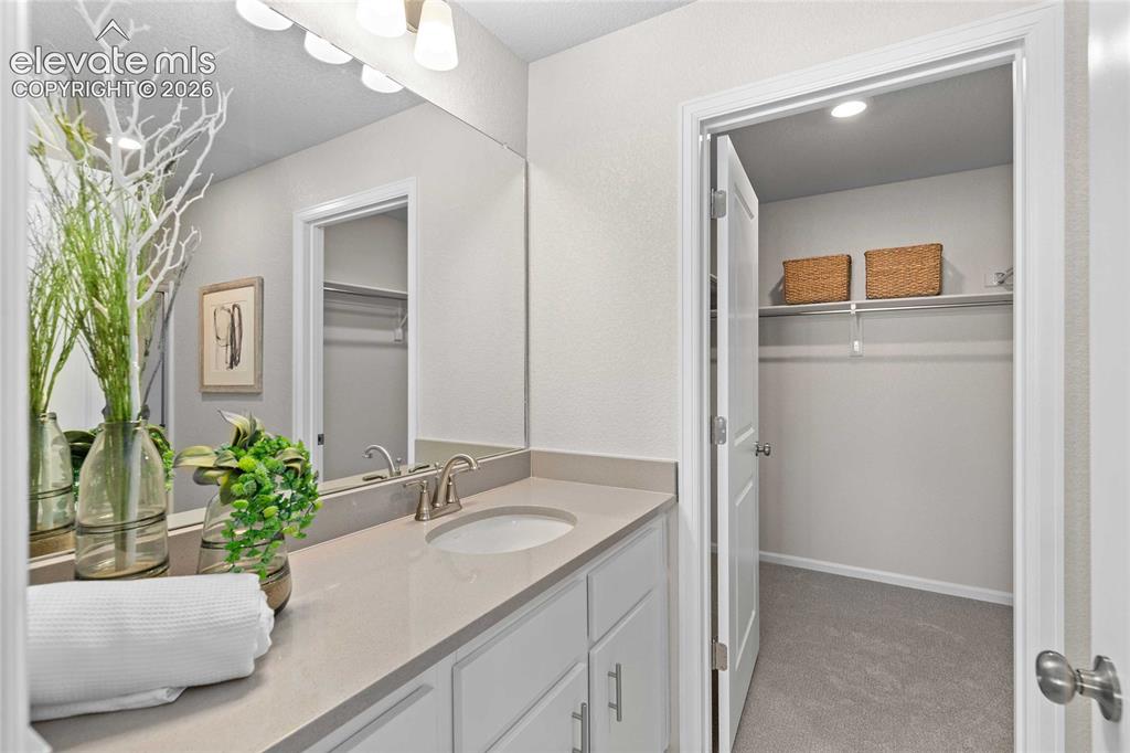 Image 14 of 25: Vanity with an integrated sink, brushed nickel faucet, large wall mirror, a