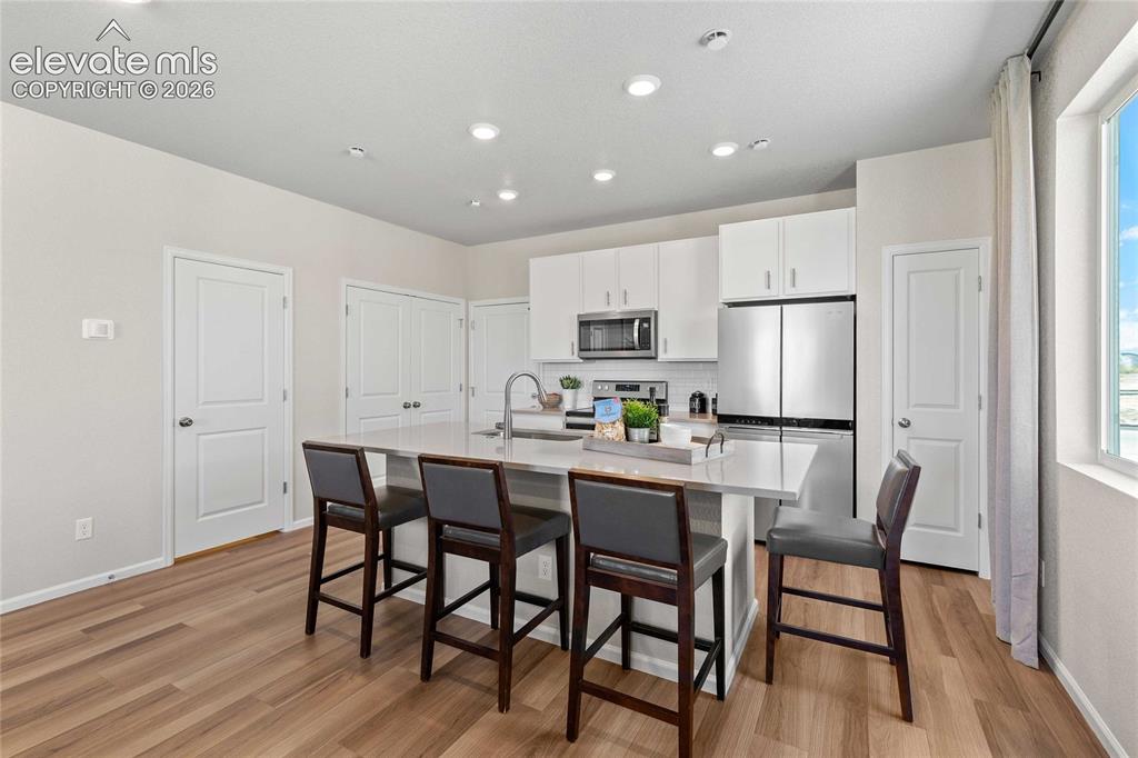 Image 2 of 25: Modern kitchen with white cabinetry and wood-finish flooring
*Photos of a 