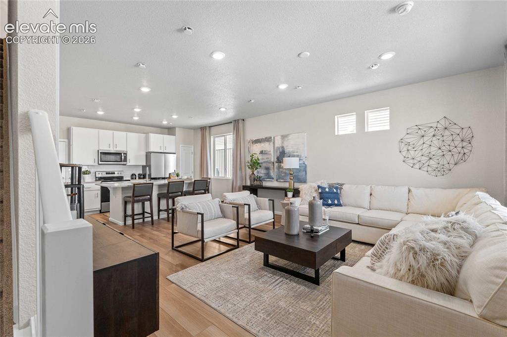 Image 4 of 25: Open-concept living area featuring wood-finish flooring, white cabinetry, s