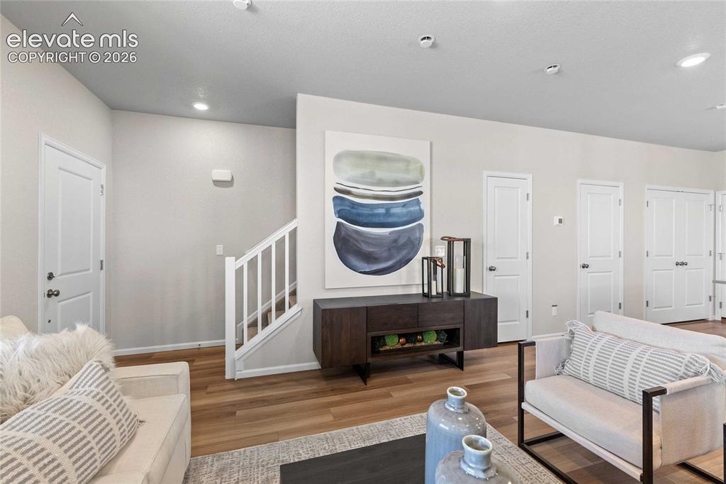 Image 8 of 25: Warm wood-finish flooring, recessed ceiling lighting, and crisp white trim