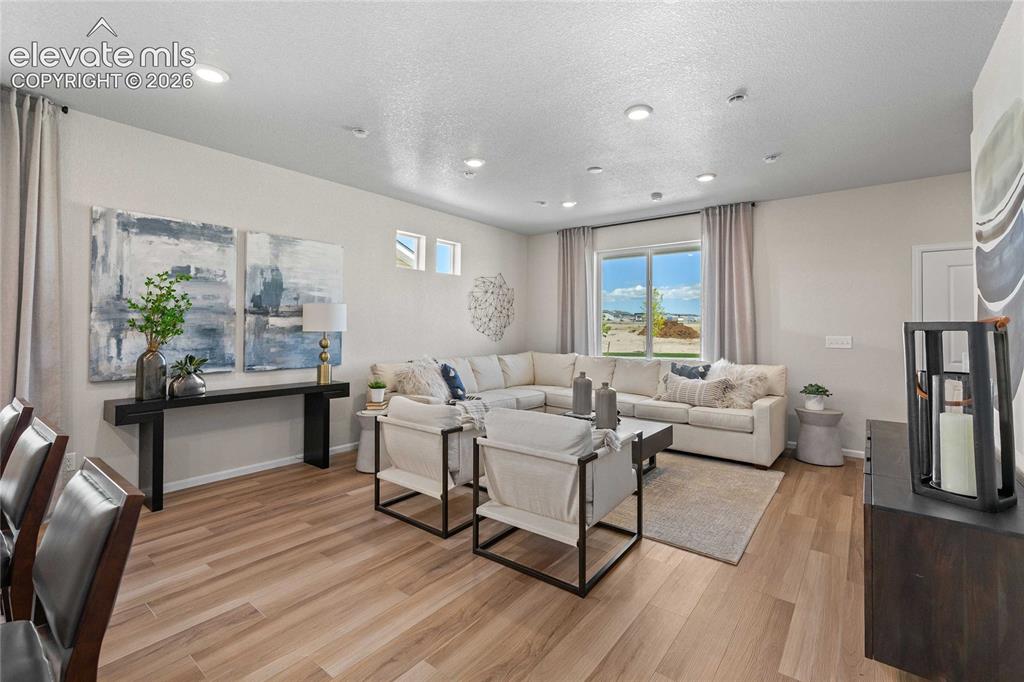 Image 9 of 25: Open-concept living area with wood-finish flooring, recessed lighting, and 
