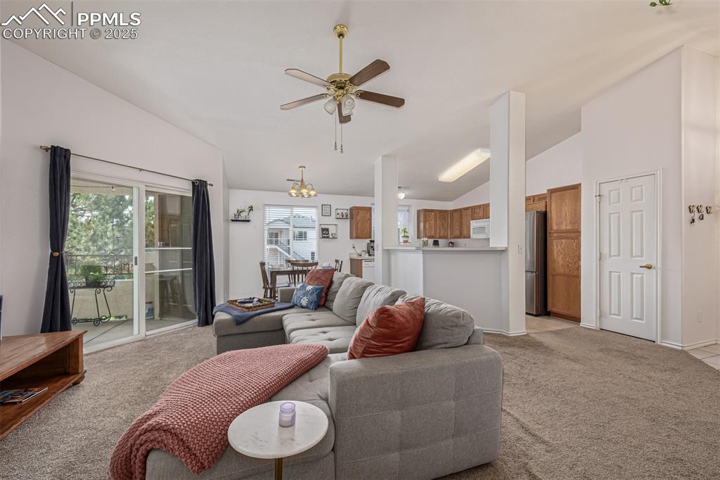 Caption: Living room with vaulted ceiling, a ceiling fan and a fireplace