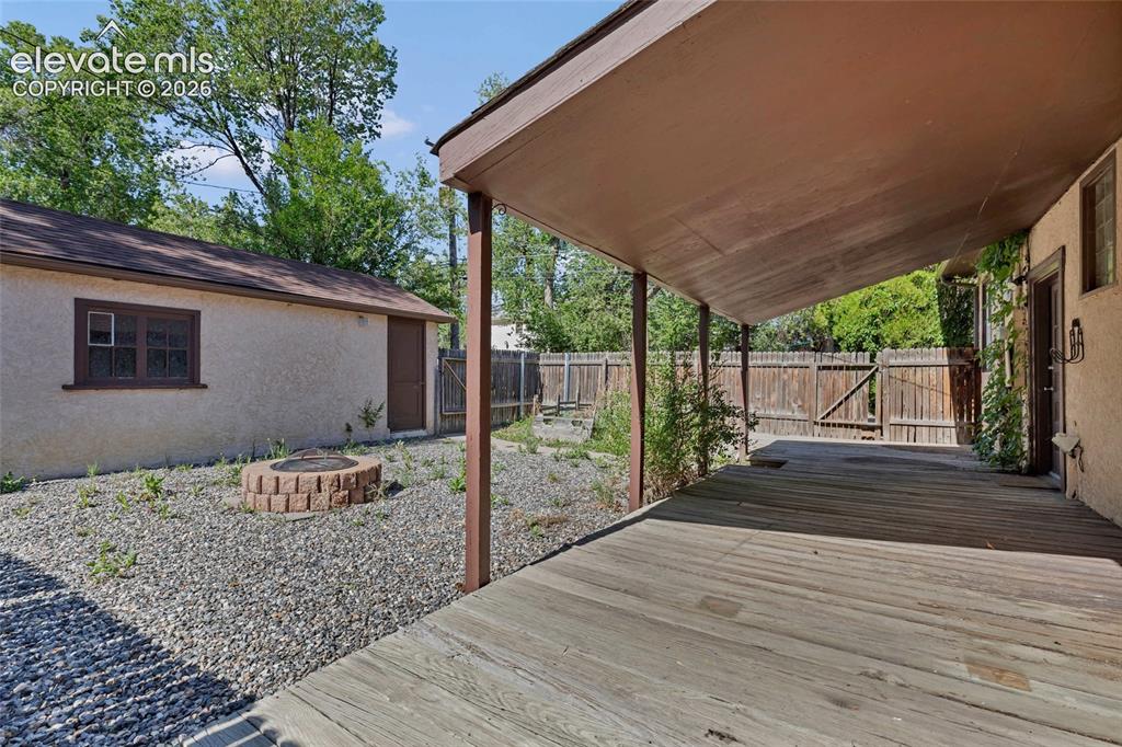 Image 38 of 39: Large, covered porch, garden beds, and fire pit