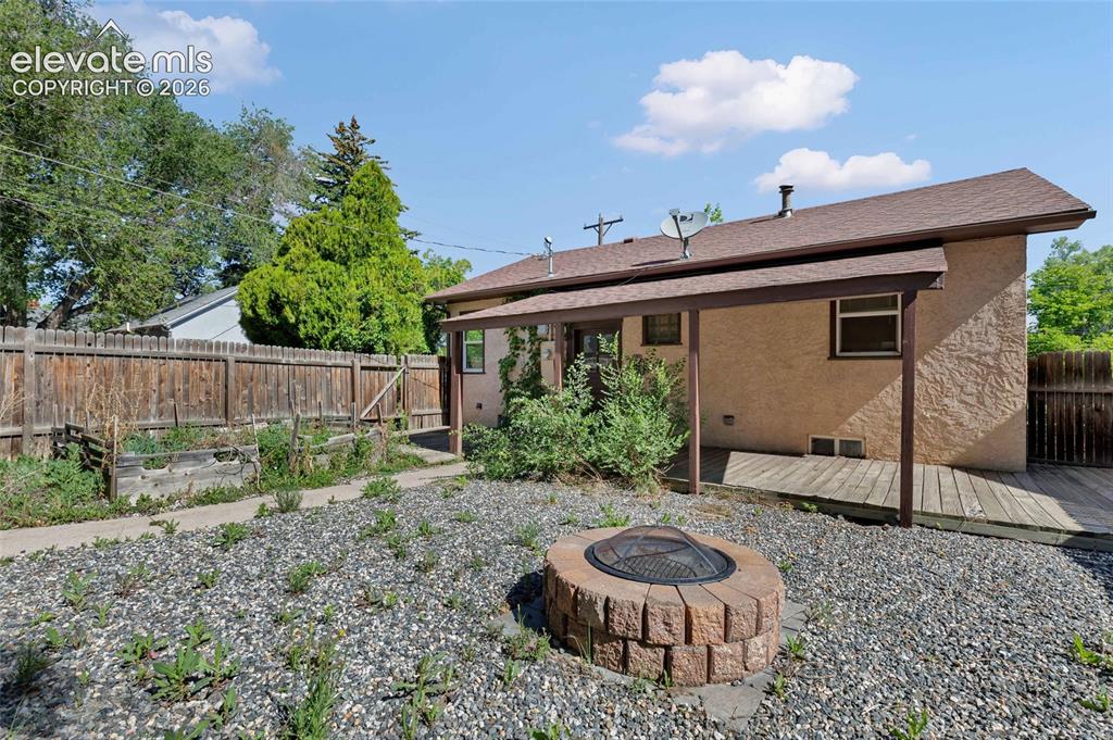 Image 5 of 39: Large, covered porch, garden beds, and fire pit