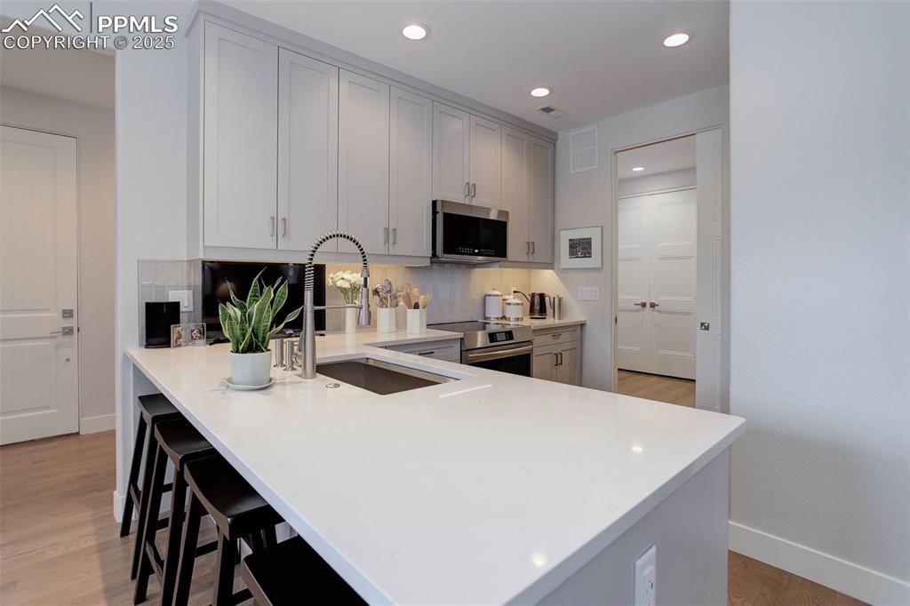 Image 10 of 32: Kitchen with light wood finished floors, stainless steel appliances, recess