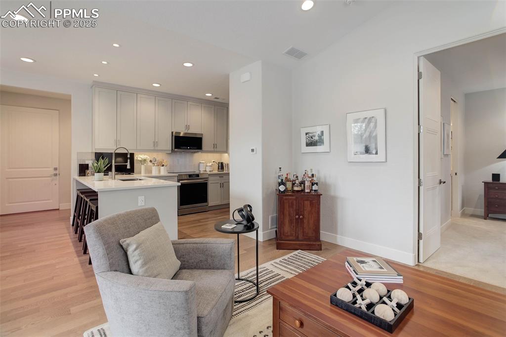 Image 16 of 32: Living room with recessed lighting and light wood finished floors