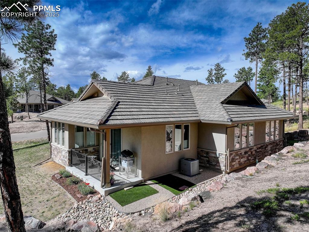Image 28 of 32: Back of house with stone siding, a sunroom, stucco siding, and a tile roof