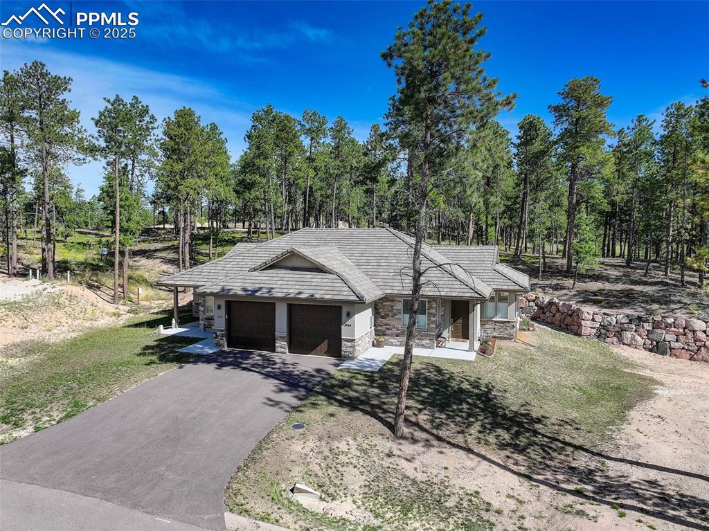 Image 30 of 32: View of front of home featuring stone siding, asphalt driveway, a garage, a