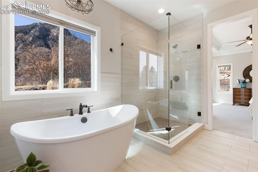 Image 21 of 49: A freestanding soaking tub is positioned beneath a large picture window, of