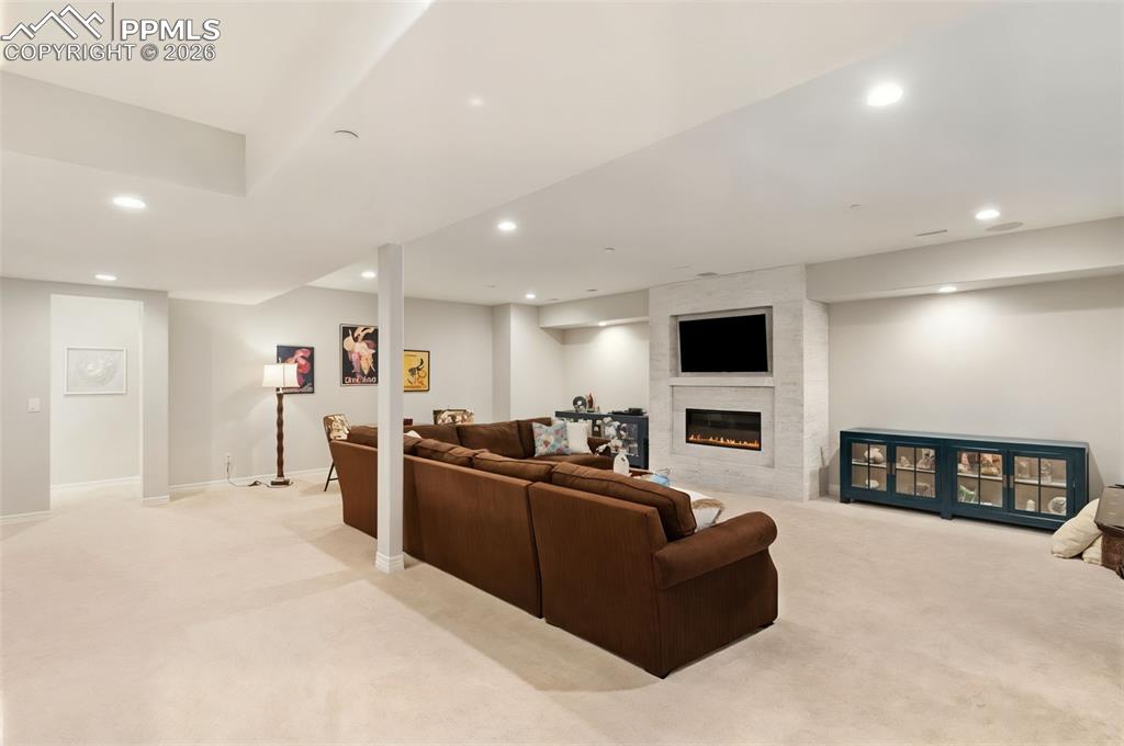 Image 27 of 49: Anchored by a second striking gas fireplace, the basement living space prov