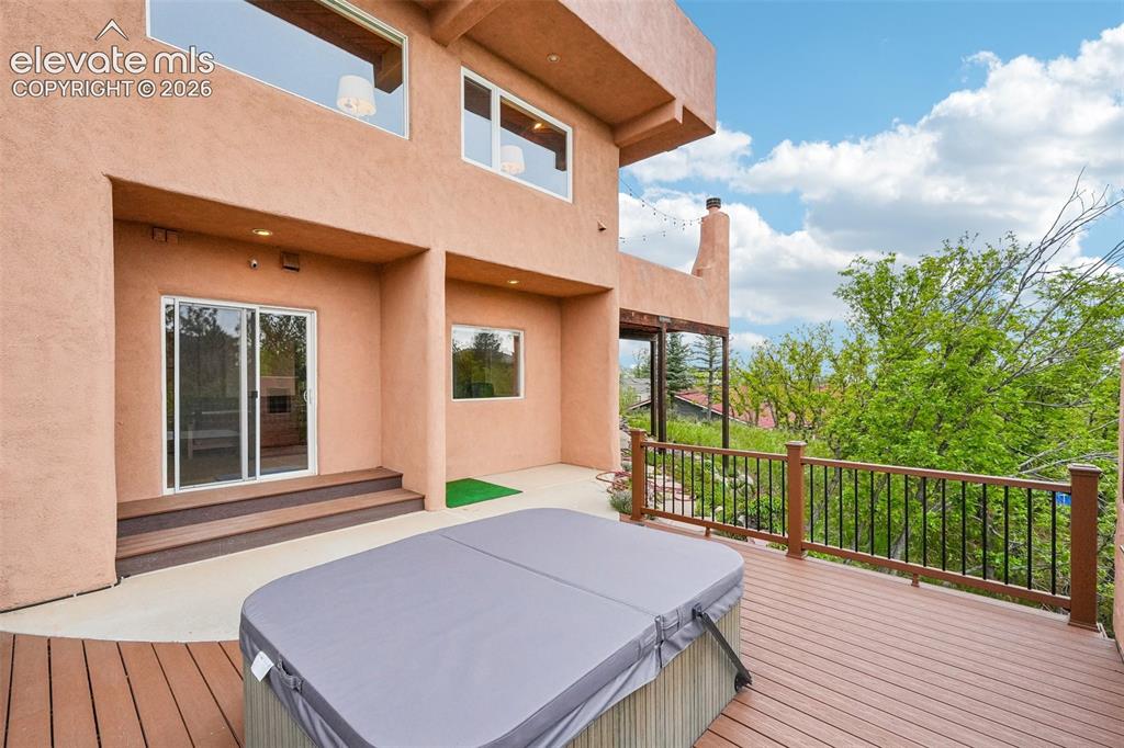 Image 43 of 50: Walk out deck featuring a hot tub and a built in smoker surrounded by natur