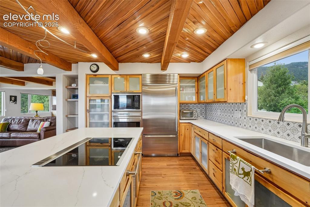 Image 9 of 50: Kitchen with quartz countertops, tile backsplash, a large island, ample cab