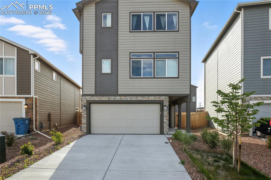 Caption: View of front of property featuring stone siding, an attached garage, and driveway