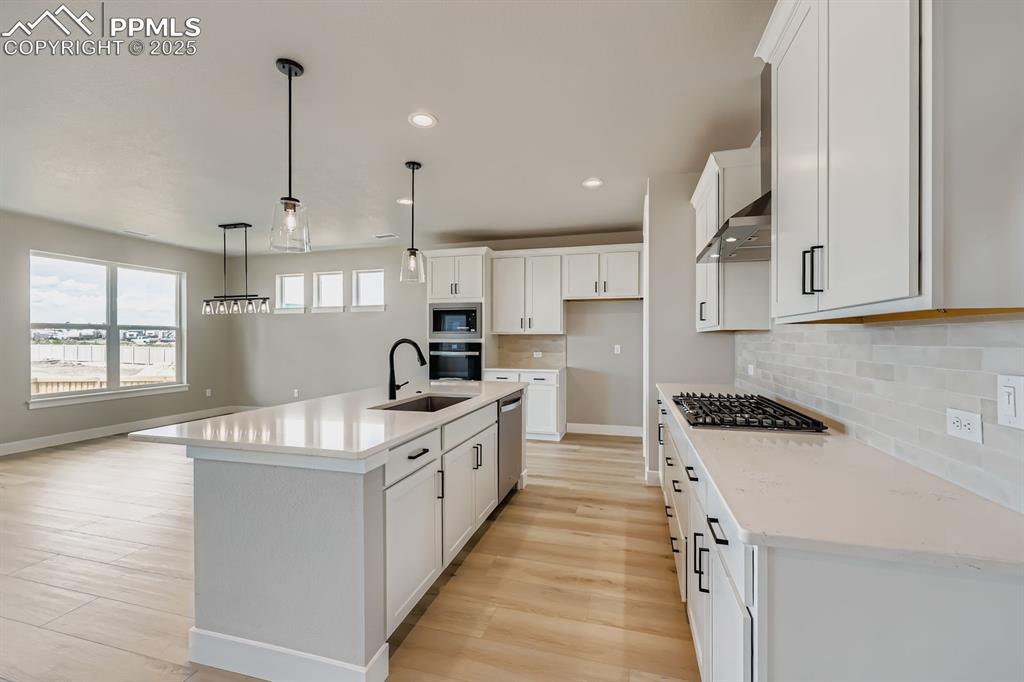 Image 11 of 28: Kitchen featuring light wood-type flooring, white cabinets, recessed lighti