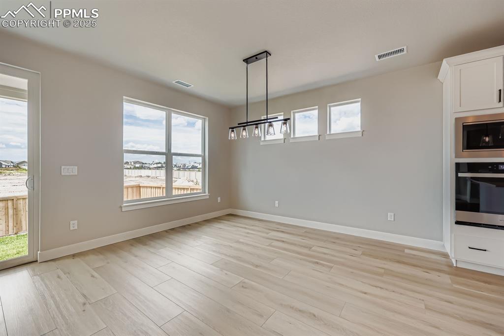 Image 12 of 28: Unfurnished dining area with plenty of natural light, light wood-style floo