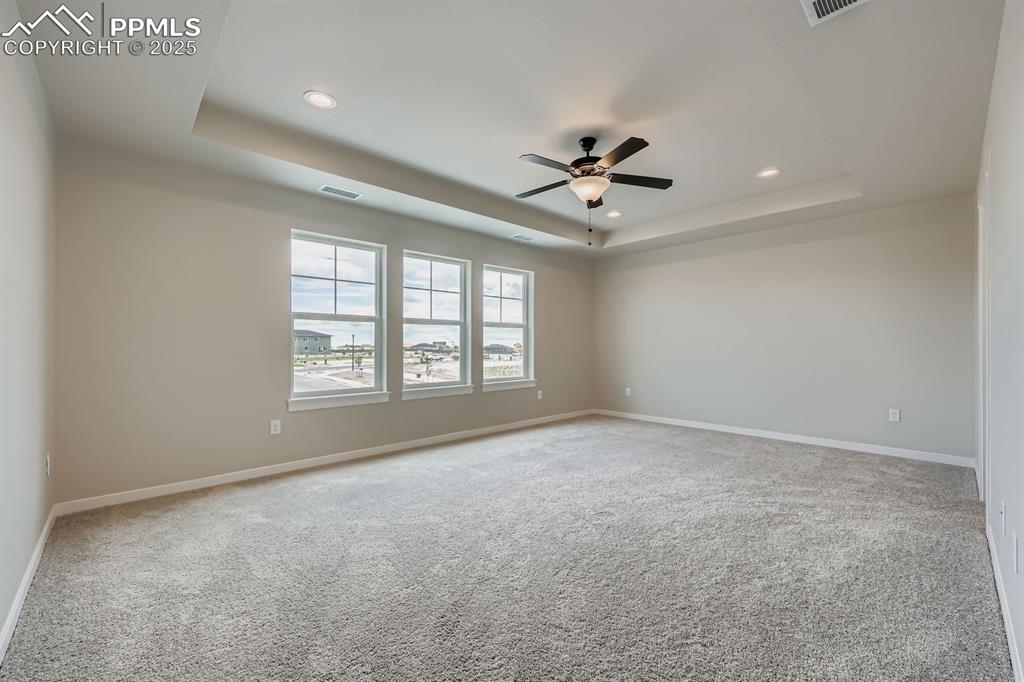 Image 15 of 28: Carpeted empty room featuring a tray ceiling, ceiling fan, and recessed lig