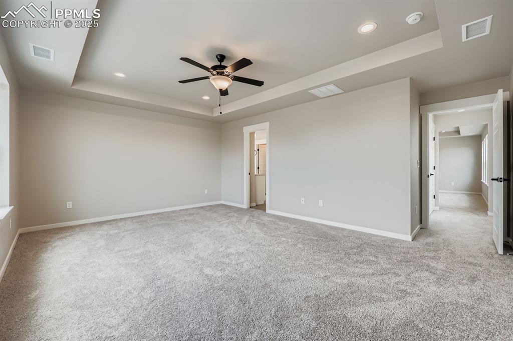 Image 16 of 28: Spare room featuring a tray ceiling, recessed lighting, light carpet, and a