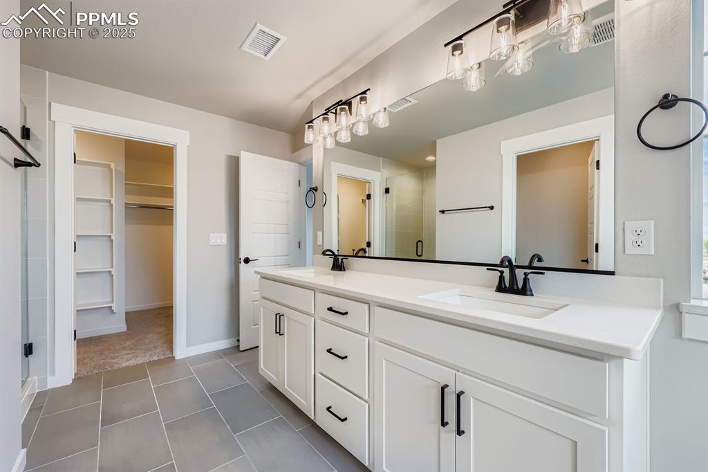 Image 17 of 28: Full bath featuring a shower stall, double vanity, a spacious closet, and t