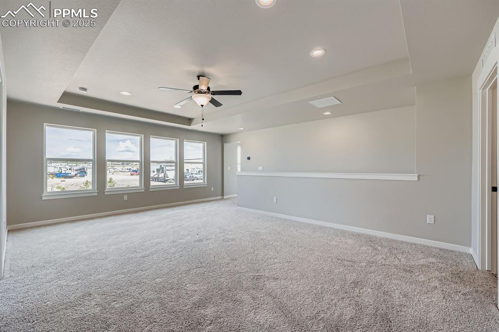 Image 24 of 28: Carpeted spare room featuring a raised ceiling, a ceiling fan, and recessed