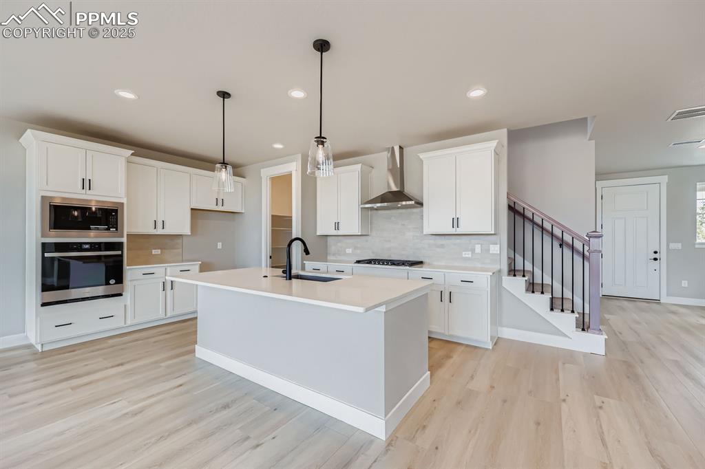 Image 8 of 28: Kitchen with appliances with stainless steel finishes, white cabinetry, lig