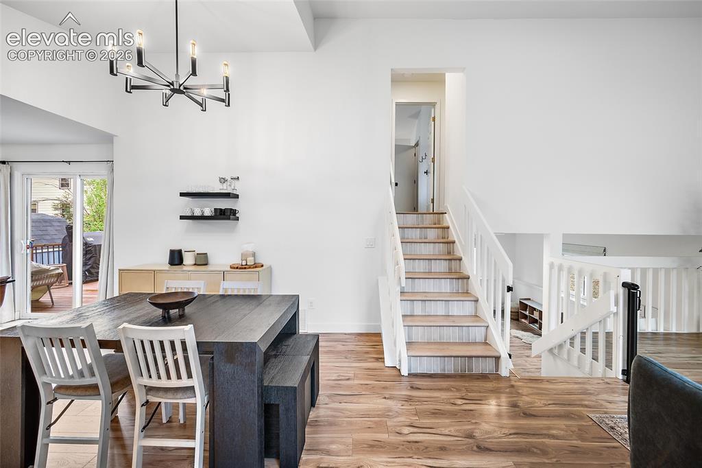 Image 11 of 50: Vaulted ceiling with a modern chandelier, wood-finish flooring, and white w