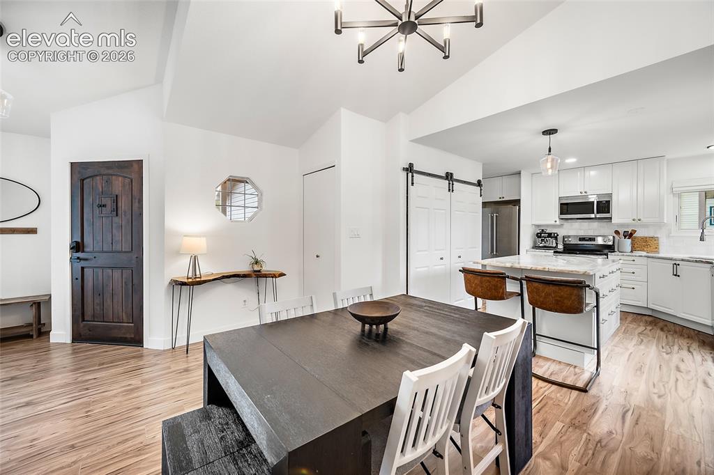 Image 12 of 50: Open-concept living space featuring wood-finish flooring, a vaulted ceiling