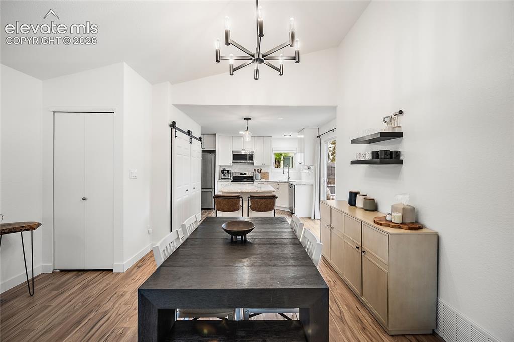 Image 13 of 50: Spacious dining area featuring vaulted ceilings, wood-finish flooring, and 