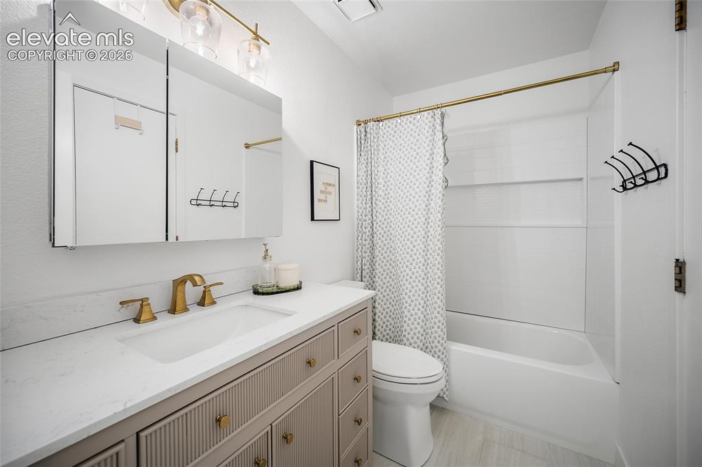 Image 24 of 50: Bathroom featuring a single vanity with stone-finish countertop, brushed br