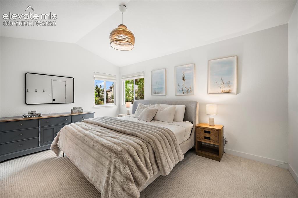 Image 25 of 50: Vaulted ceiling bedroom featuring light-colored carpeting, multiple windows