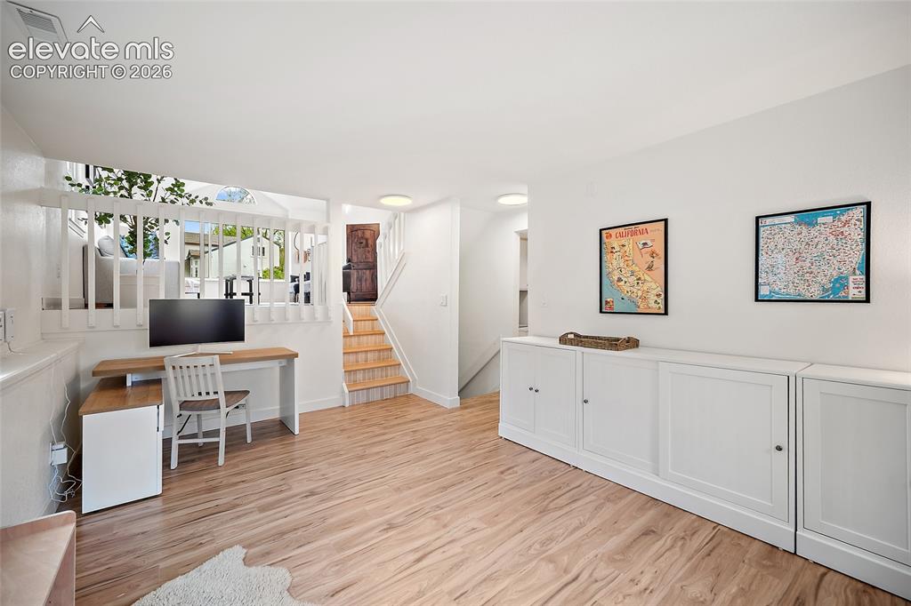 Image 32 of 50: Light wood-finish flooring complements white walls throughout this space
