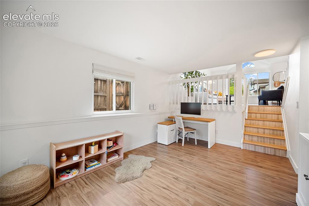 Image 33 of 50: Open recreational space featuring wood-finish flooring, a contemporary stai