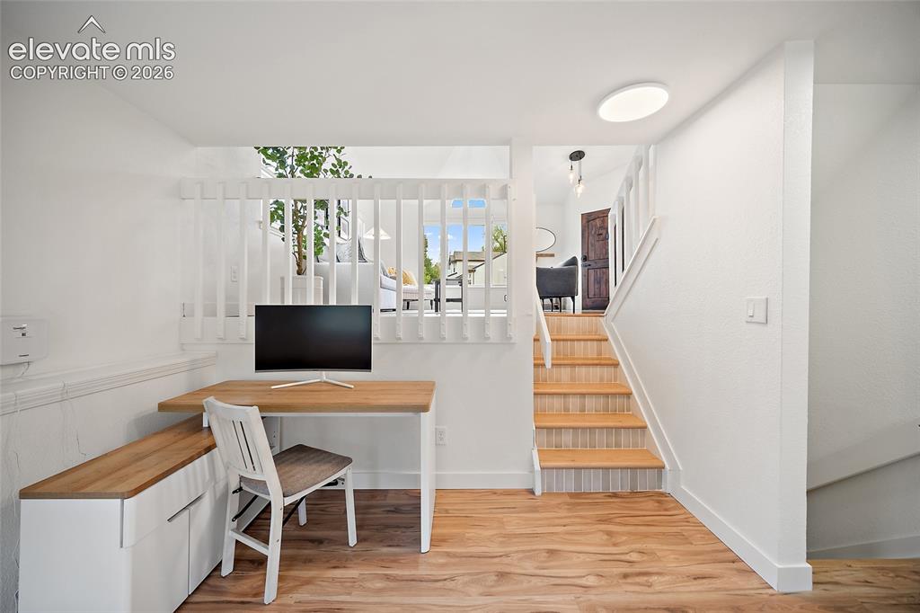 Image 34 of 50: Bright multi-use space featuring wood-finish flooring, white walls, and a b