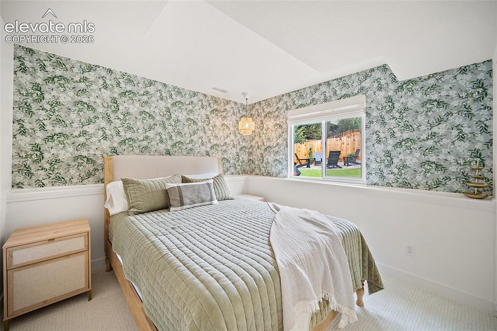 Image 36 of 50: Carpeted bedroom featuring botanical print wallpaper, a single window with 