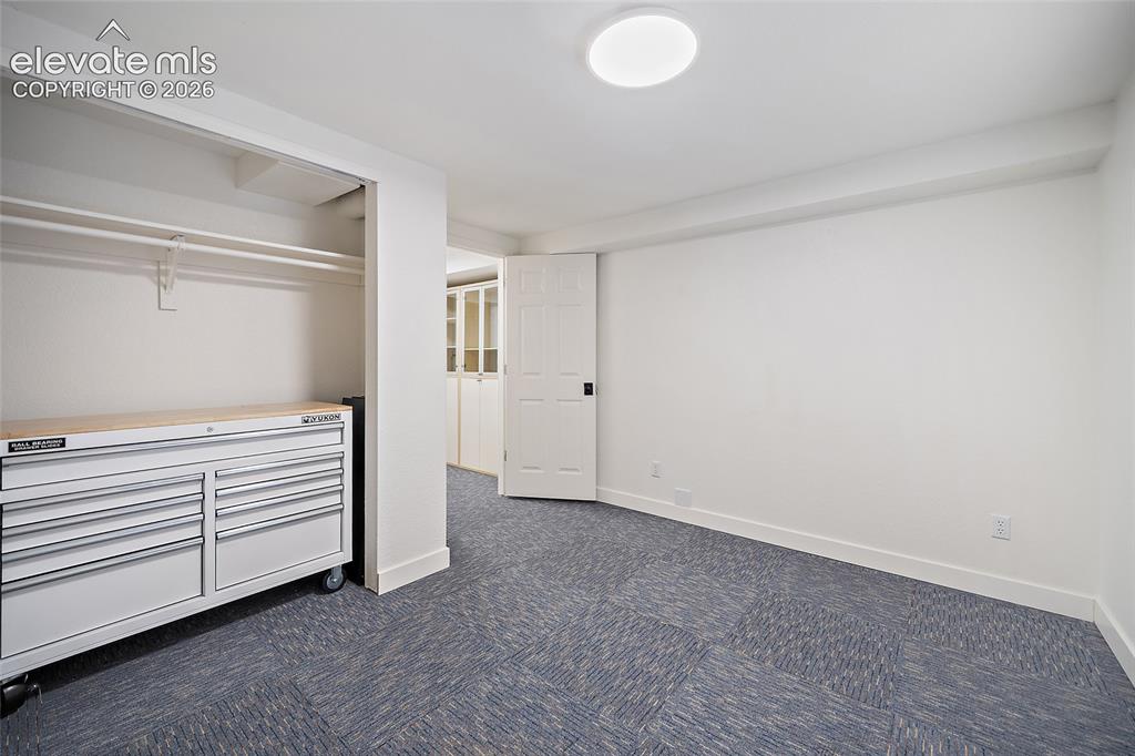 Image 41 of 50: Basement room featuring patterned carpet flooring, white walls, and a flush